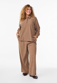 Brown corduroy two-piece outfit featuring a collared top and wide-leg pants. Accessories include dark shoes with embellishments.