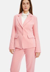 Rosa Cordhosenanzug bestehend aus einem taillierten Blazer mit zwei Knöpfen und passenden Hosen, mit einer subtilen Textur und Fronttaschen.