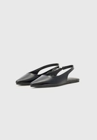 Czarne lakierowane buty typu slingback z szpiczastym noskiem, minimalistycznym designem i płaską podeszwą. Posiadają otwartą piętę i regulowany pasek.