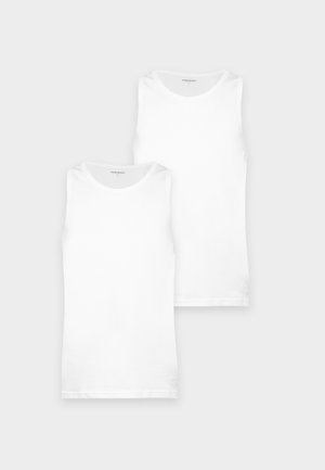Deux débardeurs blancs unis, l’un placé derrière l’autre sur un fond gris clair.