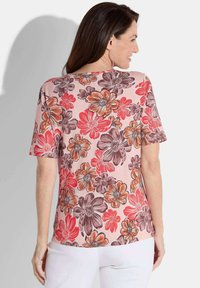 Bloemige T-shirt met korte mouwen in een roze basis, met grote oranje, rode en bruine bloemen. Zachte stof met een ontspannen pasvorm en een ronde halslijn.