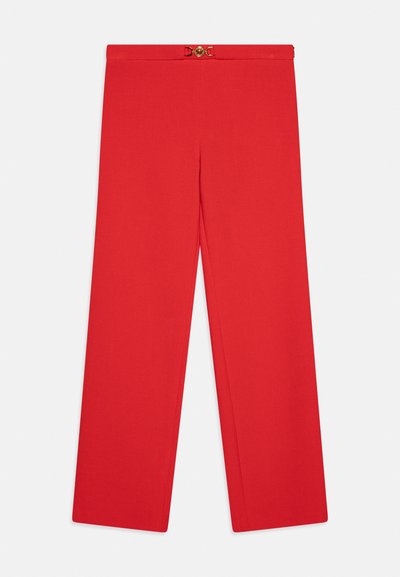 Pantalon rouge taille haute et jambes larges avec un petit détail de boucle décorative dorée à la taille.