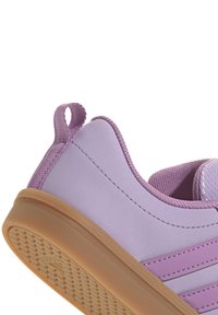 Fioletowe sneakersy z gładkiego materiału, gumową podeszwą, teksturowanym uchwytem oraz pętelką z tyłu dla łatwego zakładania. Projekt zawiera poziome paski.