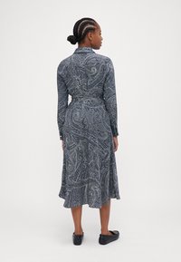 Abito a maniche lunghe blu navy con motivo paisley, vita cintrata e orlo svasato. Realizzato in tessuto morbido, con polsini e colletto abbottonati.