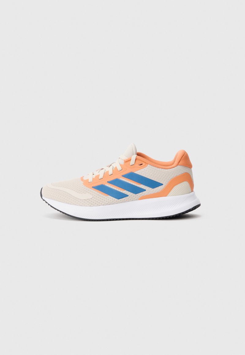 Zapatilla de correr color beige claro con detalles en naranja, franjas azules en el lateral, suela blanca y dibujo de la suela en negro, presentada sobre un fondo liso.