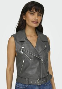 Graue, ärmellose Bikerweste aus Leder mit eingeschnittenem Revers, mehreren Reißverschlusstaschen und einem taillierten Gürtel. Strukturierte Oberfläche und metallische Hardware-Details.
