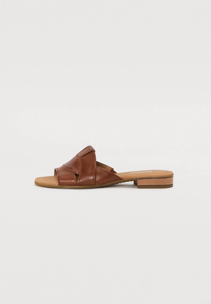 Sandali scivolati in pelle marrone con punta aperta, design a cinturini intrecciati e tacco piatto in legno. Texture liscia e hardware minimale.