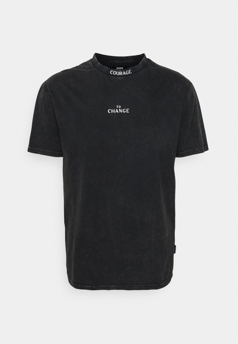 T-shirt en coton noir avec col rond, manches courtes et texture délavée. Présente un texte blanc "COURAGE TO CHANGE" sur la poitrine.