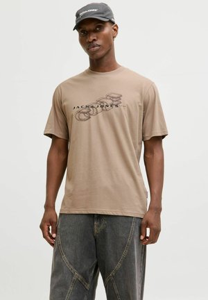 Beige bomulds t-shirt med rund halsudskæring og korte ærmer, med et sort grafisk design og logo på forsiden.