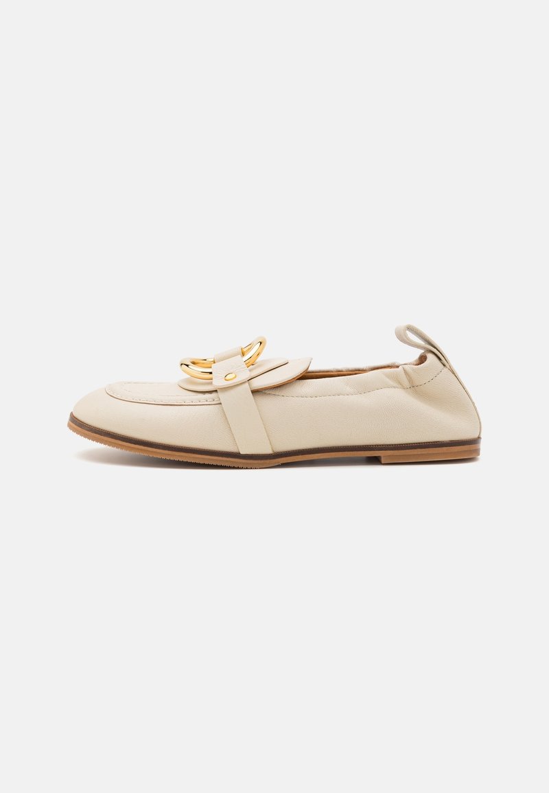 Mocassin plat en cuir beige avec détail de boucle dorée, bout arrondi, petit talon en bois et languette à l'arrière, présenté sur fond blanc.