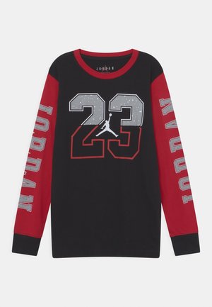 Czarna koszula z długim rękawem z czerwonymi rękawami, dużą cyfrą "23" i sylwetką koszykarza z przodu oraz napisem "JORDAN" na każdym rękawie w szarych literach.