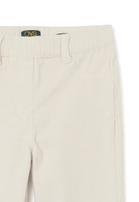 Lichtbeige corduroy broek met een textuur ribpatroon, elastische tailleband en voorzakken. Merkenlabel zichtbaar bij de taille.