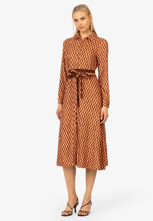 Lang, knopenjurk in roest en bruine geometrische print, met een cinched taille en bijpassende riem. Beschikt over lange mouwen en een vloeiende silhouet.