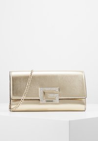 Pochette métallisée dorée avec bandoulière chaîne, dotée d'une fermeture à logo ornée de cristaux et d'une finition texturée lisse. Design rectangulaire compact.