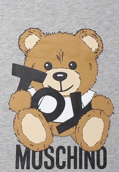 Il tessuto grigio presenta un orsetto di cartone con pelliccia marrone, che tiene in mano un cartello nero con la scritta "Toy", sopra la parola "Moschino" in testo nero.