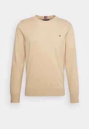 Beiger Pullover mit Rundhalsausschnitt, langen Ärmeln, kleinem rot-weiß-blauem Logo auf der linken Brust sowie gerippten Bündchen an Ärmeln und Saum.