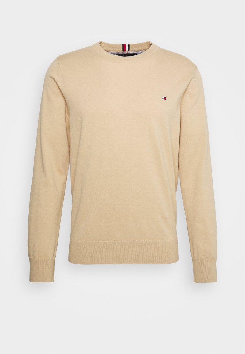 Pull beige à manches longues avec col rond, petit logo rouge, blanc et bleu sur la poitrine gauche, et finitions en bord-côte aux poignets et à l'ourlet.