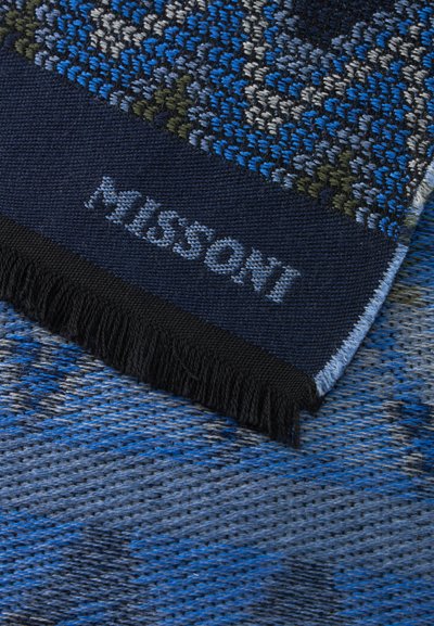 Tissu tissé bleu à motifs avec une frange foncée et "MISSONI" brodé en bleu clair sur une bordure bleue unie.