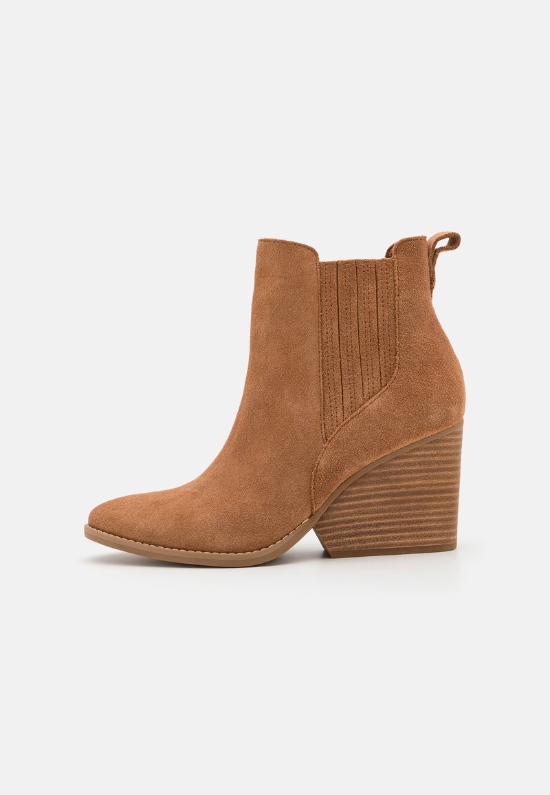 Bottines en suede marron avec un bout pointu, des panneaux latéraux côtelés et un talon empilé. Équipées d'une languette pour un enfilage facile.
