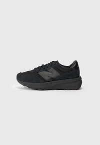 Chaussures de sport noires avec une tige en daim et en mesh, présentant un bout arrondi, une semelle intercalaire proéminente et un design minimaliste avec un accent de logo.