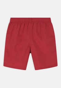 Røde badebukser med elastisk linning. Glatt, lett materiale; over-kneet lengde; enkel design uten mønstre eller aksenter.