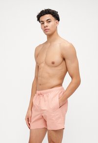 Svijetlo ružičaste kupaće hlače napravljene od laganog materijala s elastičnim pojasom, s bočnim otisnutim logotipom "Calvin Klein".