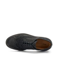 Scarpa nera da uomo con dettagli in brogue, con lacci e suola liscia, posizionata su uno sfondo bianco.