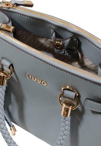 Gr�å læderhåndtaske med en tekstureret overflade, gulddetaljer, fletede remaccenter og en indvendig foring med logomønster.