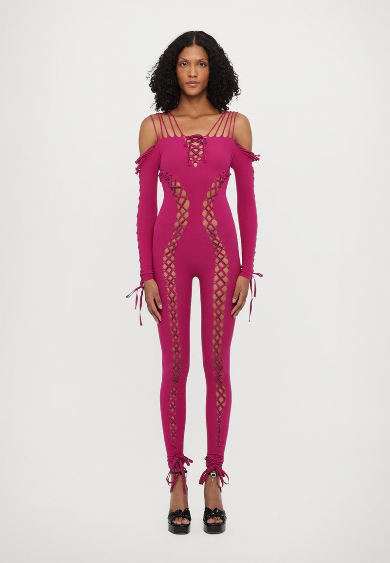Salopetă fucsia, lungă, cu design off-shoulder, curea șnur în față, decupaje pe laterale și accente legate la mâneci și glezne. Textură netedă.