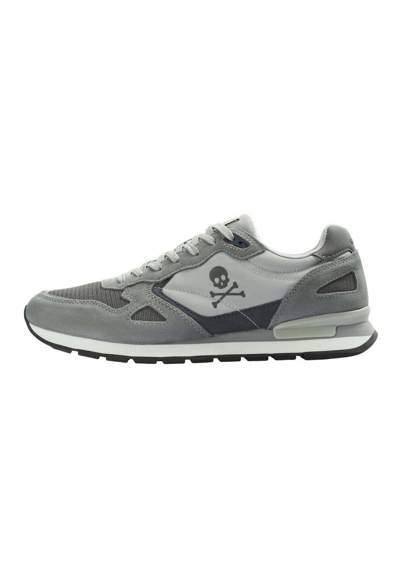 Graue Sneaker aus Wildleder und Mesh-Materialien, mit einem Low-Top-Design und einem Totenkopf-und-Kreuzbein-Logo an der Seite. Schwarze Gummisohle.