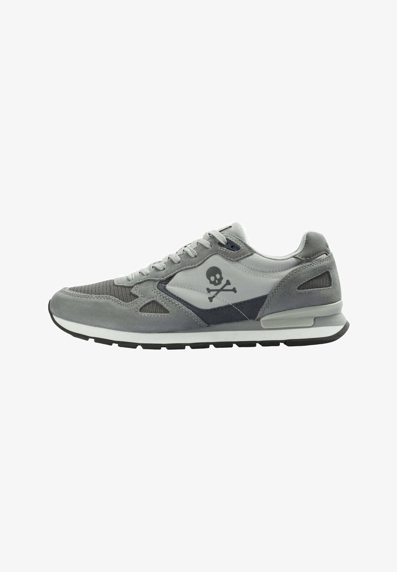 Graue Sneaker aus Wildleder und Mesh-Materialien, mit einem Low-Top-Design und einem Totenkopf-und-Kreuzbein-Logo an der Seite. Schwarze Gummisohle.