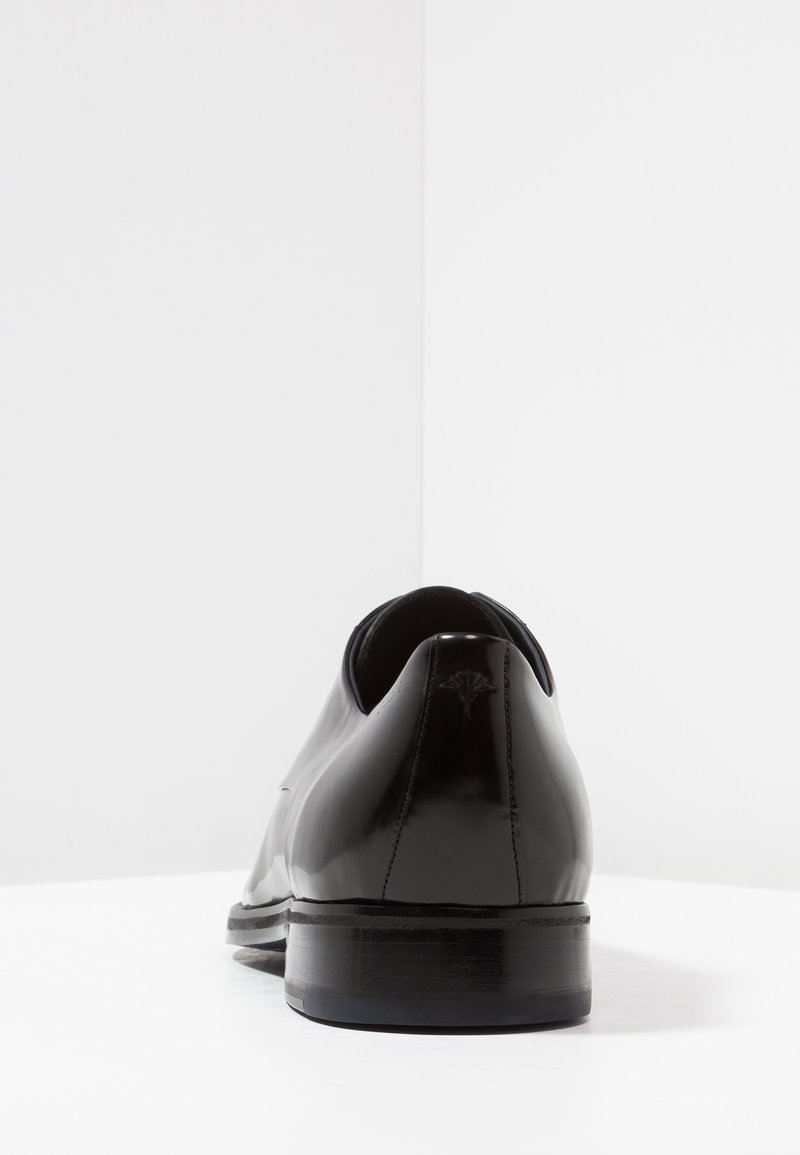 Schwarze Leder-Absatzschuhe mit einem eleganten Design, runder Zehenpartie und einer glatten, glänzenden Oberfläche mit einem dezenten Logo-Detail an der Ferse.