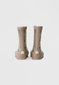 Botas de chuva de borracha castanhas com padrão floral, acabamento texturizado, forro branco e sola de borracha sólida. Borda superior reforçada e acabamentos no calcanhar.