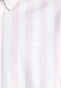 Camisa de corte recto de manga corta con rayas verticales en rosa y blanco, que presenta un pequeño logo blanco en el lado izquierdo y un diseño de cuello clásico.