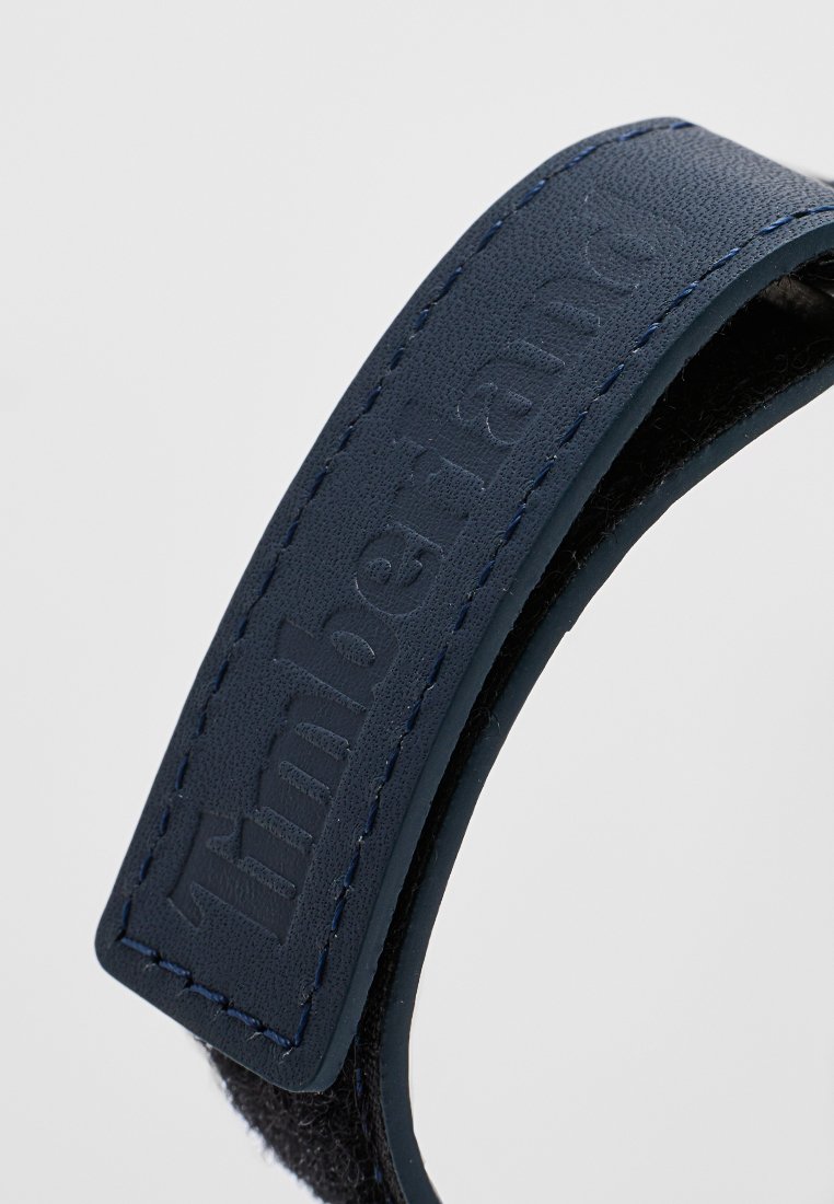 Primer plano de una correa de velcro azul de Timberland con el nombre de la marca grabado y bordes cosidos.