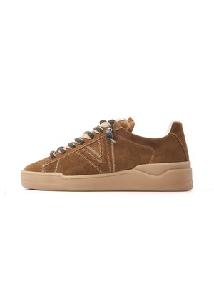 Brązowy zamszowy niskoprofilowy sneaker z beżową podeszwą i czarno-białymi paskowanymi sznurowadłami, widziany z boku na białym tle.