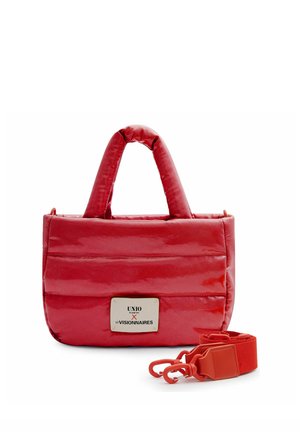 Rote, gepolsterte Handtasche mit kurzen Griffen, rechteckigem Metall-Logo und abnehmbarem breitem Riemen mit Verschlüssen vor weißem Hintergrund.