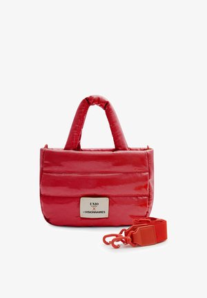 Red padded handbag with short handles, rectangular metal brand plate, and detachable wide strap with clasps on a white background.