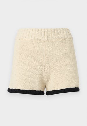 Shorts en tricot couleur crème avec taille côtelée et bordure noire à l'ourlet, présentés sur un fond clair uni.