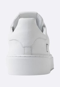 Zapatillas blancas de cuero con textura suave, talón redondeado y diseño minimalista; cuentan con costuras sutiles y una suela de plataforma baja.