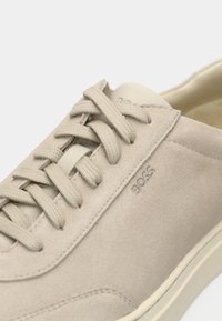 Beige suede casual sneaker with cream laces, cream sole, and subtle "BOSS" branding on the side panel.