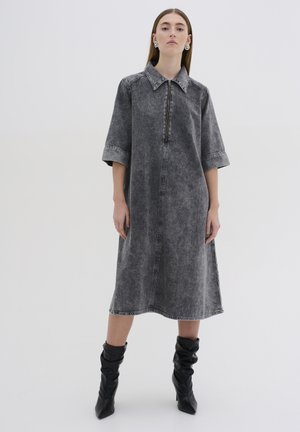 Gray denim dress with a zippered front, collar, and short sleeves. Features a relaxed fit and visible stitching accents. Worn with black knee-high boots.