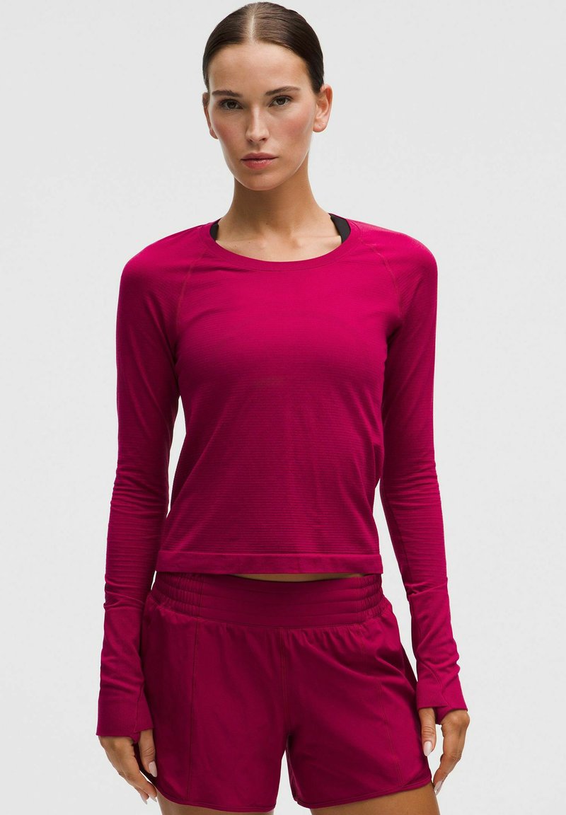Magenta sportieve longsleeve top met lange mouwen en een ronde hals, gecombineerd met bijpassende shorts met een elastische tailleband.