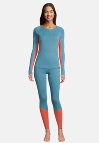 Maglietta a maniche lunghe blu e leggings abbinati con accenti corallo. Realizzati in tessuto testurizzato, presentano un collo arrotondato e un design aderente.