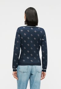 Πουλόβερ πλεκτό σε ναυτικό μπλε με μικρό μοτίβο άγκυρας, ριμπ μανσέτες και τελείωμα, σε κλασική γραμμή. Το ύφασμα φαίνεται λείο και ελαφρύ.