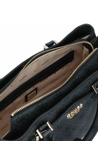 Sac à main synthétique noir avec fermeture éclair, extérieur texturé et quincaillerie dorée. L'intérieur est doublé de tissu avec un motif logo répété.