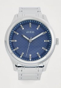 Montre en métal argenté avec un cadran bleu texturé, des index et aiguilles argentés. Dotée d'une lunette texturée et d'un bracelet en acier inoxydable.