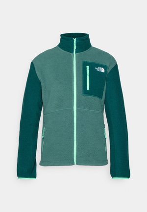 Fleece jacket met een hoge kraag, groene en teal kleurblokken, volledige ritssluiting aan de voorkant en een borstzak met ritssluiting. Logo op de zak.