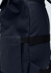 Zaino navy realizzato in materiale sintetico liscio, dotato di una tasca laterale, spallacci testurizzati con logo e chiusura a coulisse nella parte superiore.