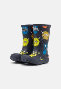Bottes de pluie en caoutchouc bleu marine avec des graphismes de monstres colorés en jaune, bleu et orange. Semelle texturée pour une meilleure adhérence et bord renforcé.
